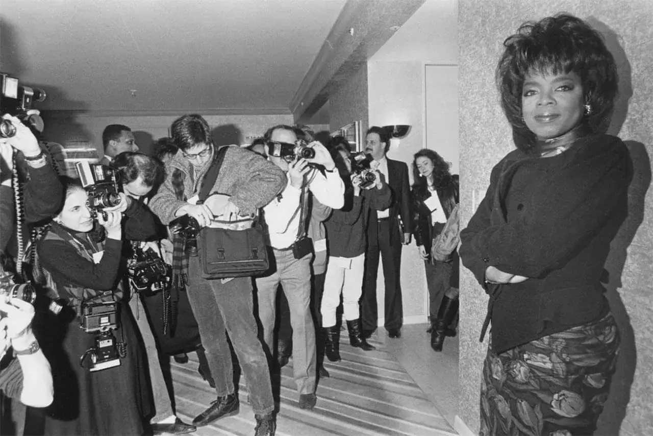 Une photographe femme américaine capture l'instant, entourée de confrères, tandis qu'Oprah Winfrey pose, imperturbable.