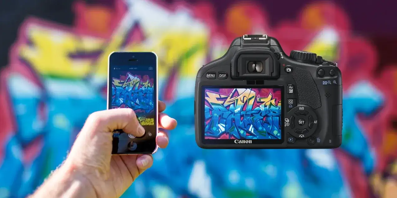 Un smartphone capture un graffiti coloré, à côté d'un appareil photo Canon affichant la même œuvre.