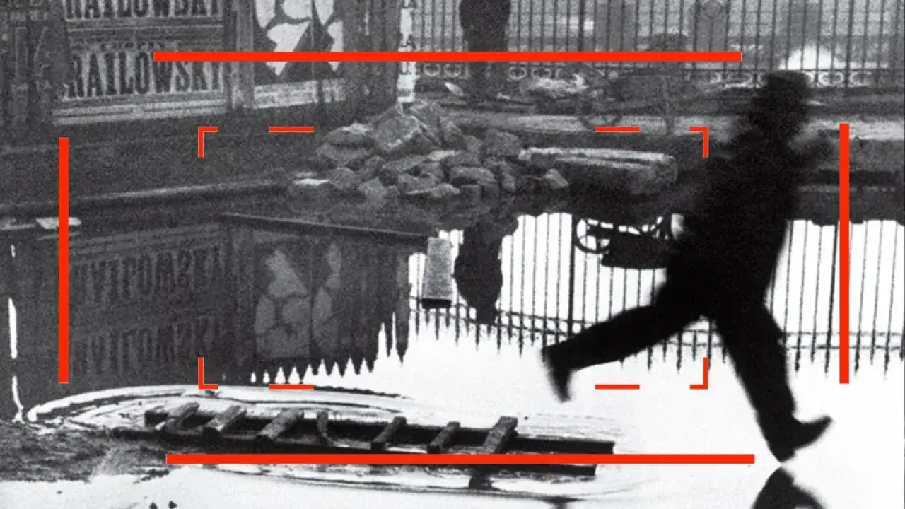 Un homme en chapeau court sur une flaque d'eau, reflet d'une sc&egrave;ne urbaine. Une des henri cartier bresson photos c&eacute;l&egrave;bres.