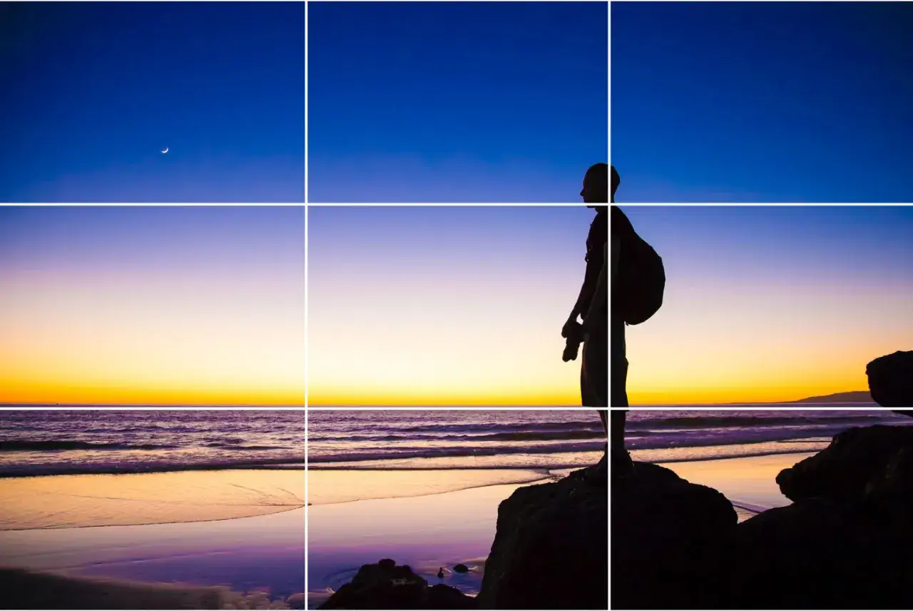 Coucher de soleil sur la plage, un photographe silhouette sur un rocher, respectant la règle des tiers cinéma.