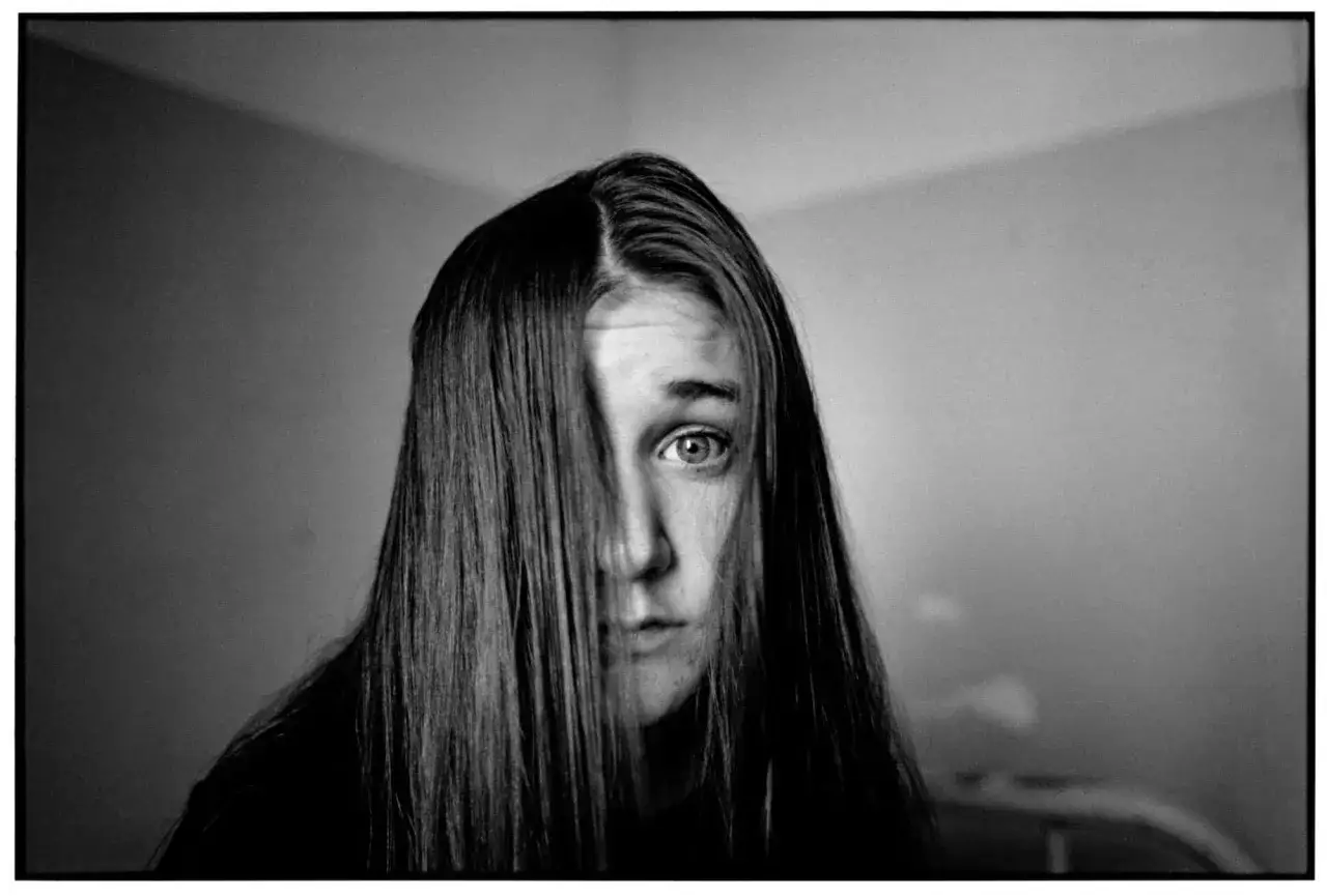 Un regard intense à travers une cascade de cheveux, dans le style de Mary Ellen Mark.