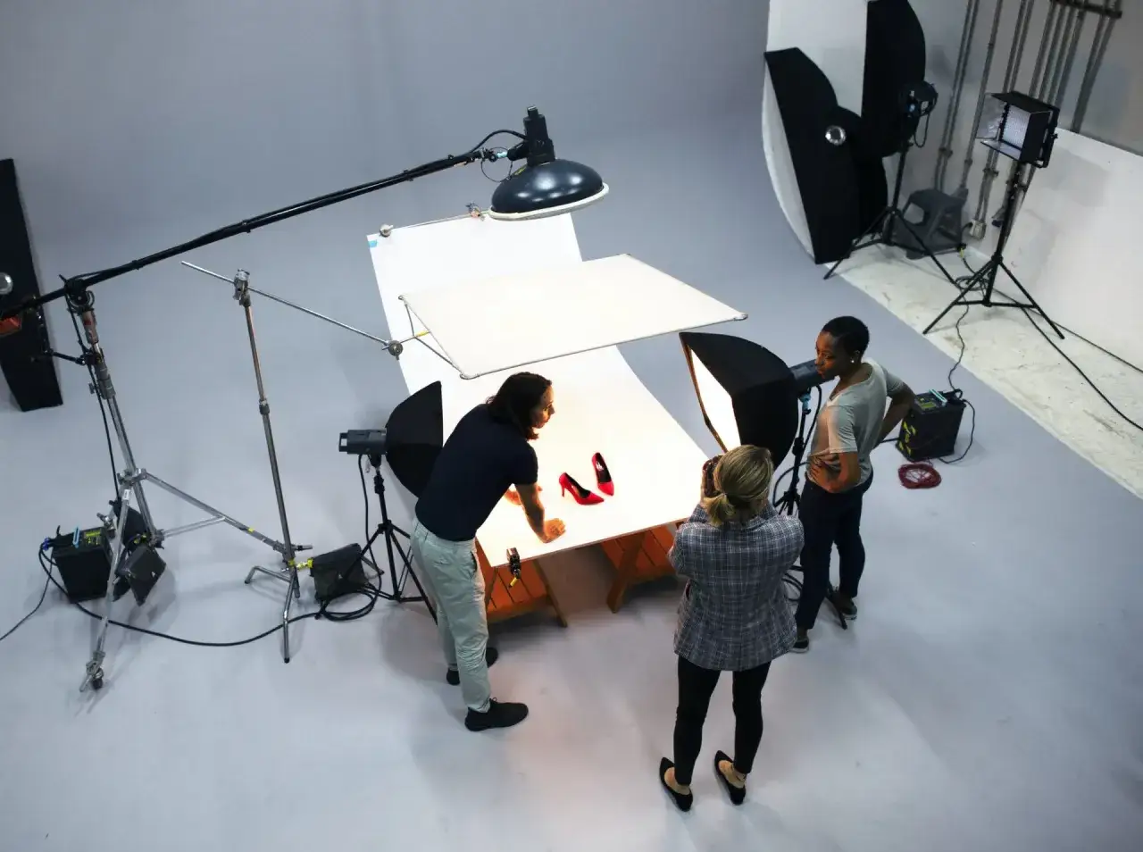 Une &eacute;quipe r&eacute;alise une photographie de produits de chaussures rouges dans un studio.