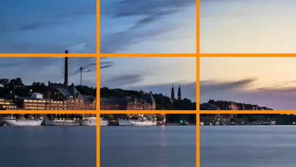 Pour comment prendre une belle photo, utilisez la règle des tiers pour cadrer ce paysage urbain au crépuscule avec des bateaux sur l'eau.