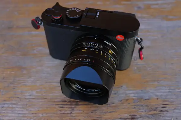 Leica Q3 test : un appareil photo noir élégant avec un objectif Summilux sur fond de bois.