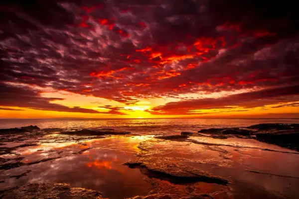 Coucher de soleil spectaculaire avec des nuages rougeoyants. Quel filtre ND pour coucher de soleil aurait pu capturer cette intensité ? La mer reflète les couleurs flamboyantes.