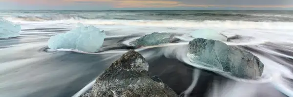 Glace sur sable noir, l'eau file en rubans soyeux grâce à la pose longue. Des diamants de glace flottent sur la plage islandaise.