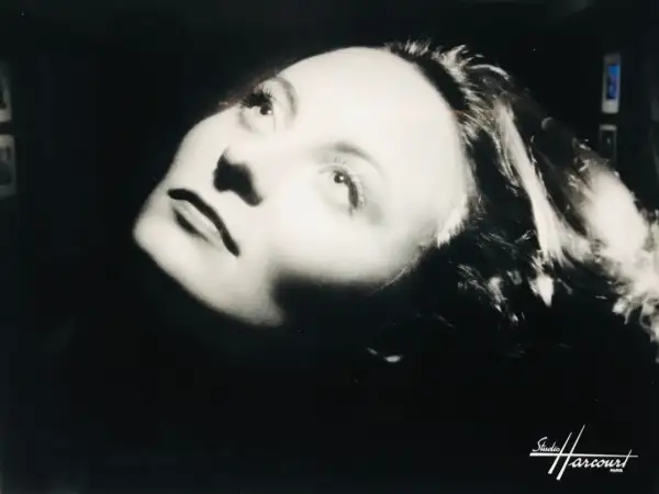 Portrait dramatique d'une femme, éclairée par le bas, évoquant l'histoire du Studio Harcourt.