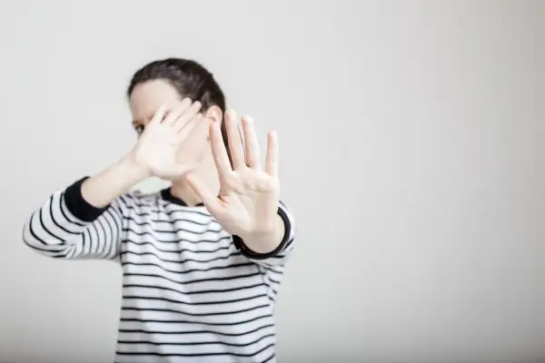 Une femme en pull rayé lève les mains pour se protéger, comme dans un exemple de copyright photo.